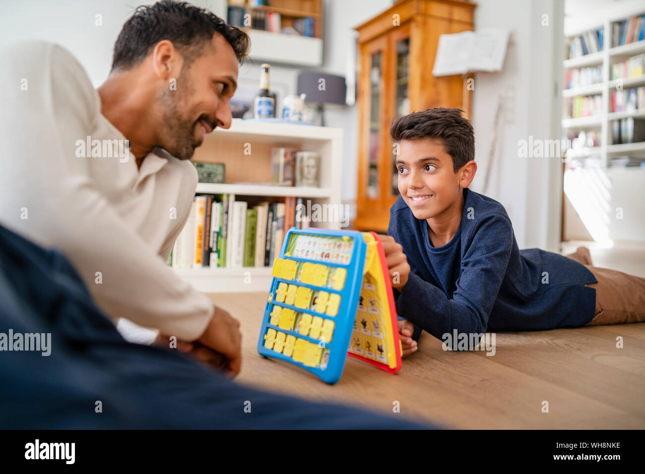 Padre e figlio sdraiato sul pavimento a casa la riproduzione di un gioco Foto Stock