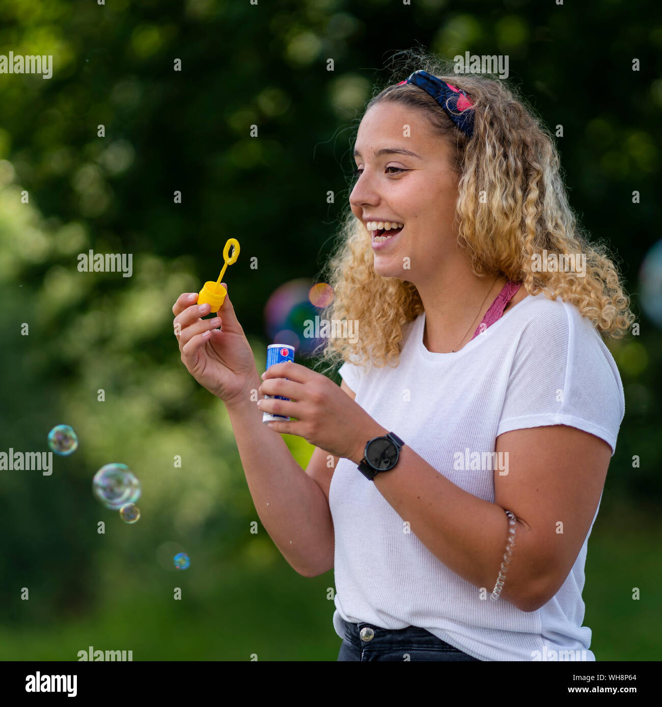 Ridendo donna bionda rendendo le bolle di sapone Foto Stock