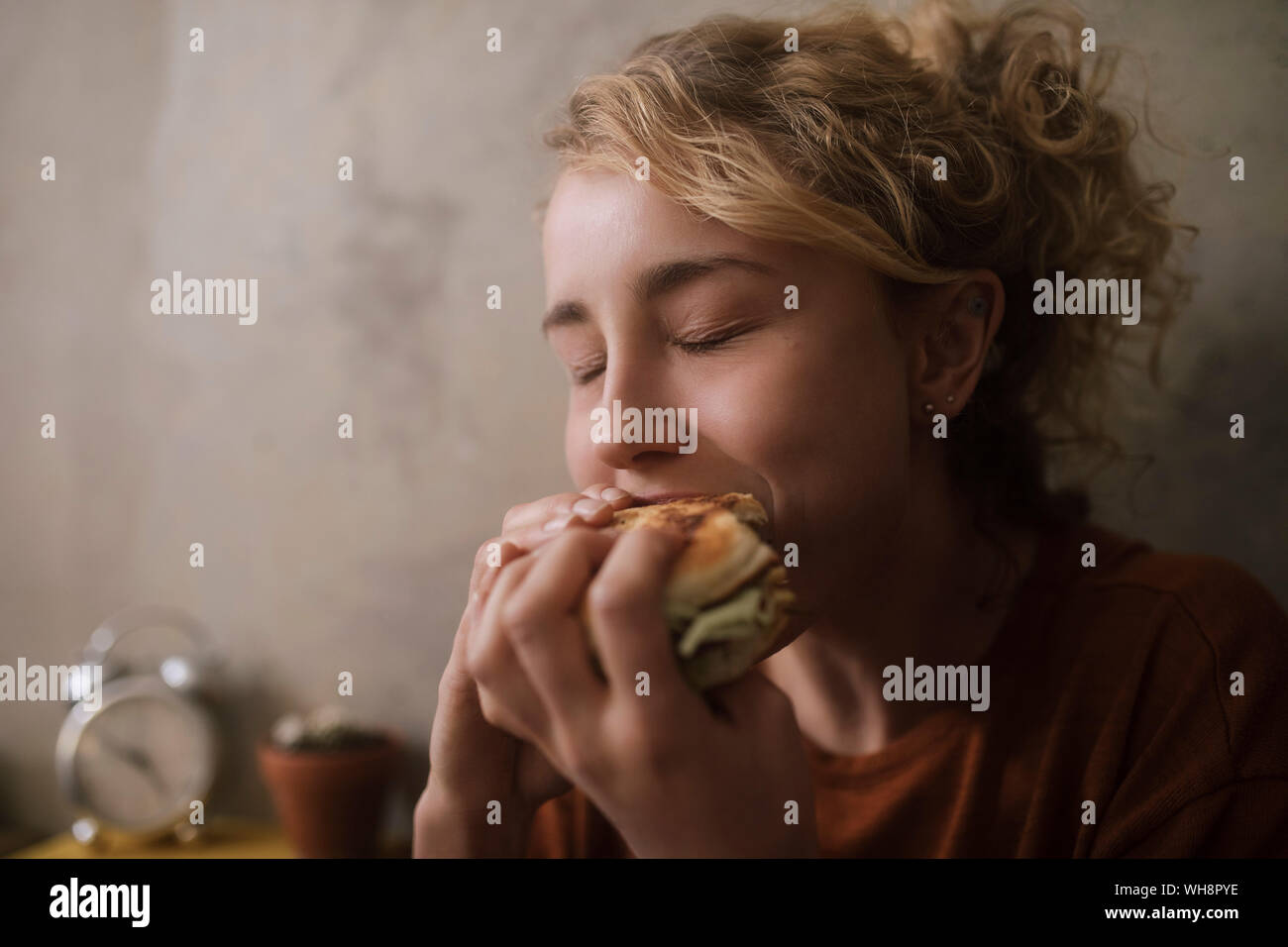 Ritratto di giovane donna di mangiare hamburger Foto Stock