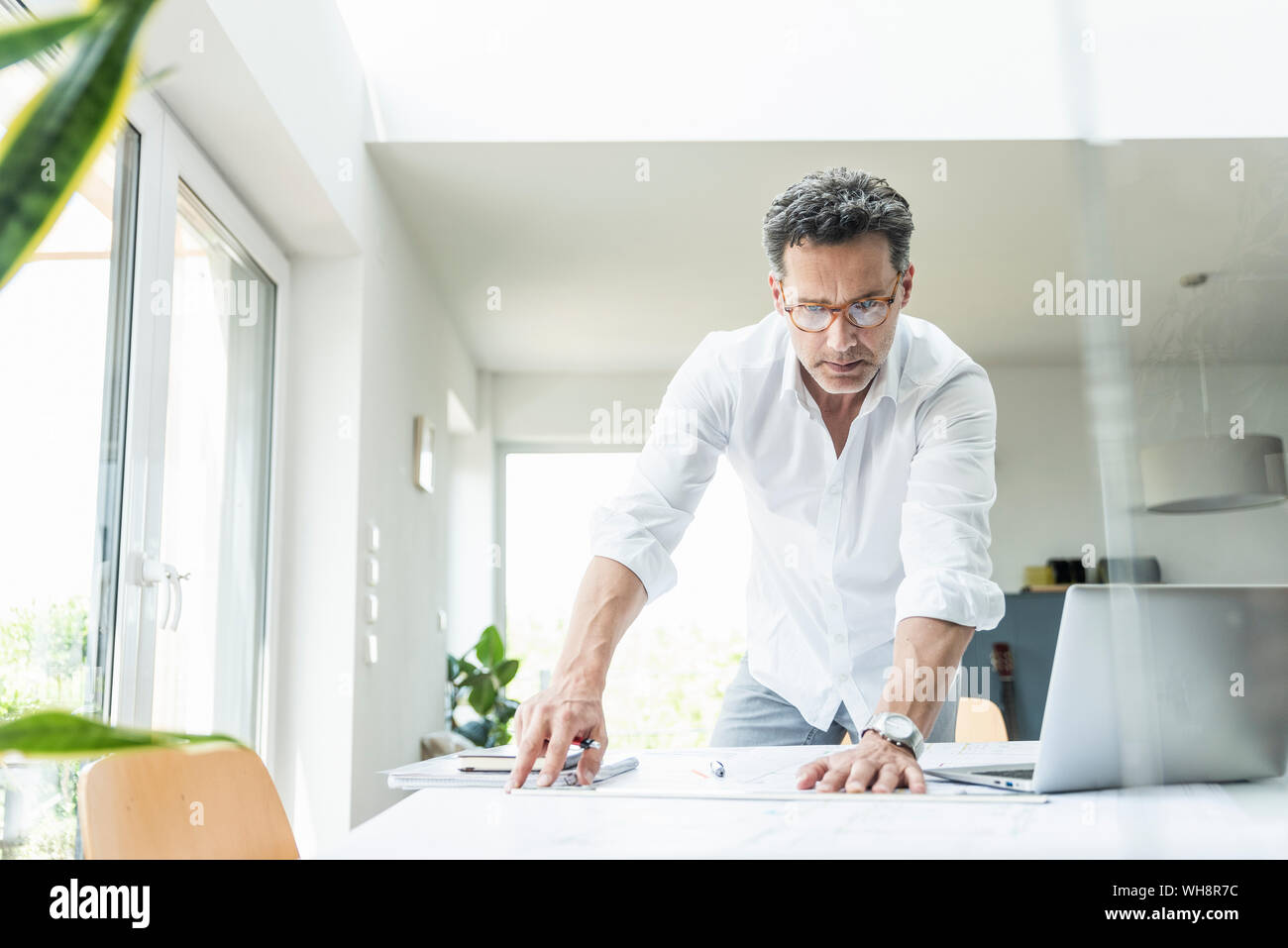 Architetto lavora sul progetto in un luminoso ufficio con computer portatile Foto Stock