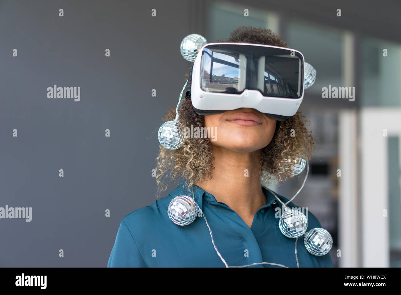 Sorridente giovane donna con la catena delle luci utilizzando occhiali per realtà virtuale Foto Stock