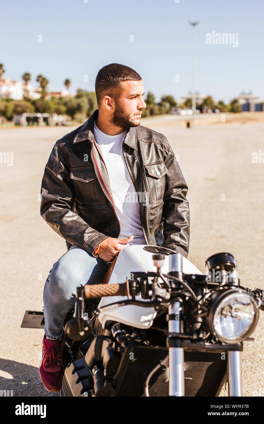 Ritratto di giovane barbuto uomo seduto sulla sua moto Foto Stock