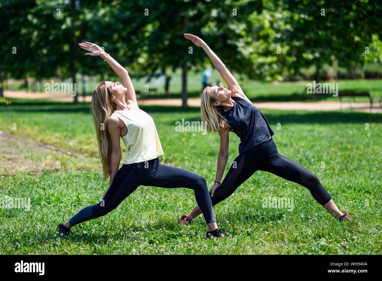 Donna matura a praticare lo yoga con sua figlia in un parco Foto Stock