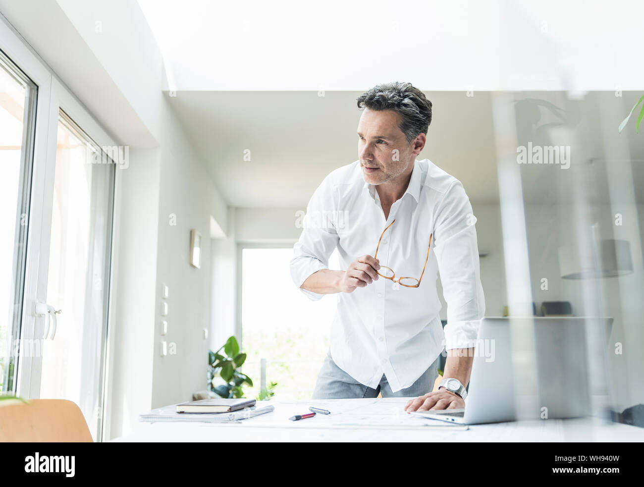 Architetto lavora sul progetto in un luminoso ufficio con computer portatile Foto Stock