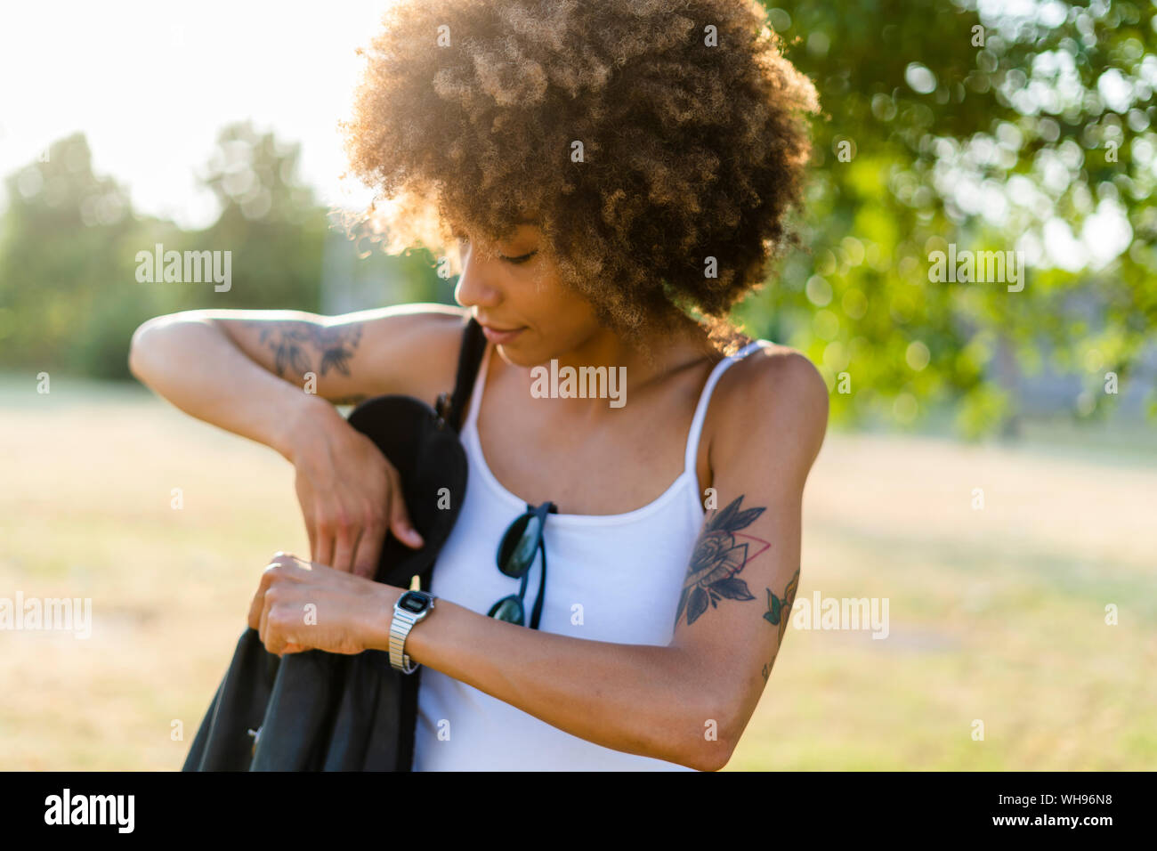 Tatuato giovane donna con borsa a tracolla in estate Foto Stock