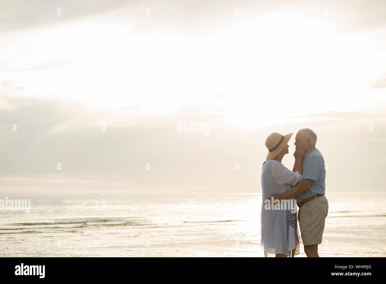 Coppia senior in piedi faccia a faccia sulla spiaggia dal tramonto, Liepaja, Lettonia Foto Stock