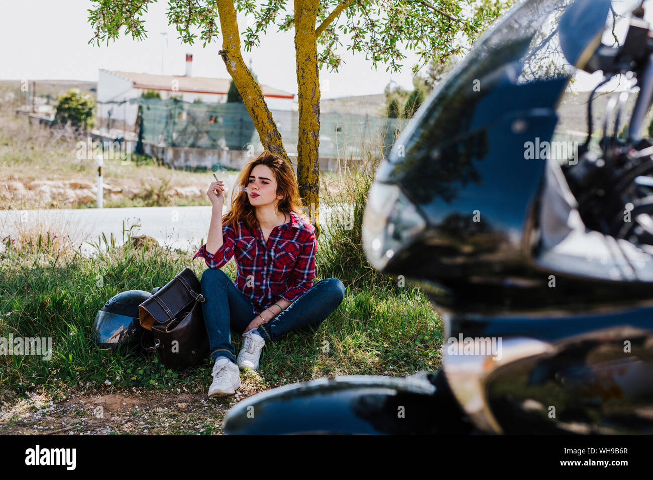 Motociclista aventi pausa sigaretta sotto un albero Foto Stock