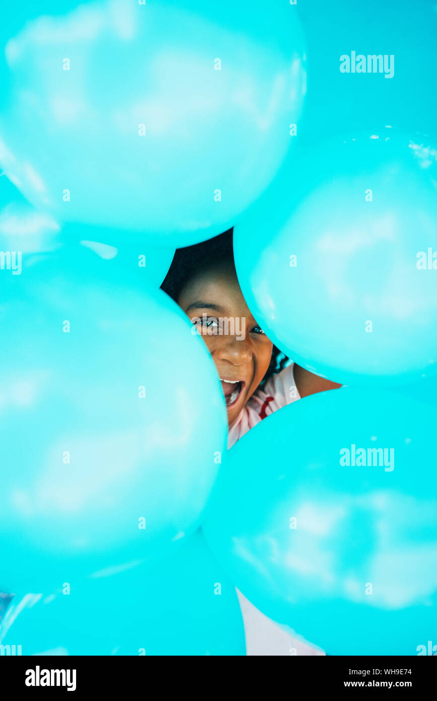Bambina di fronte ad una parete blu, tenendo palloncini Foto Stock