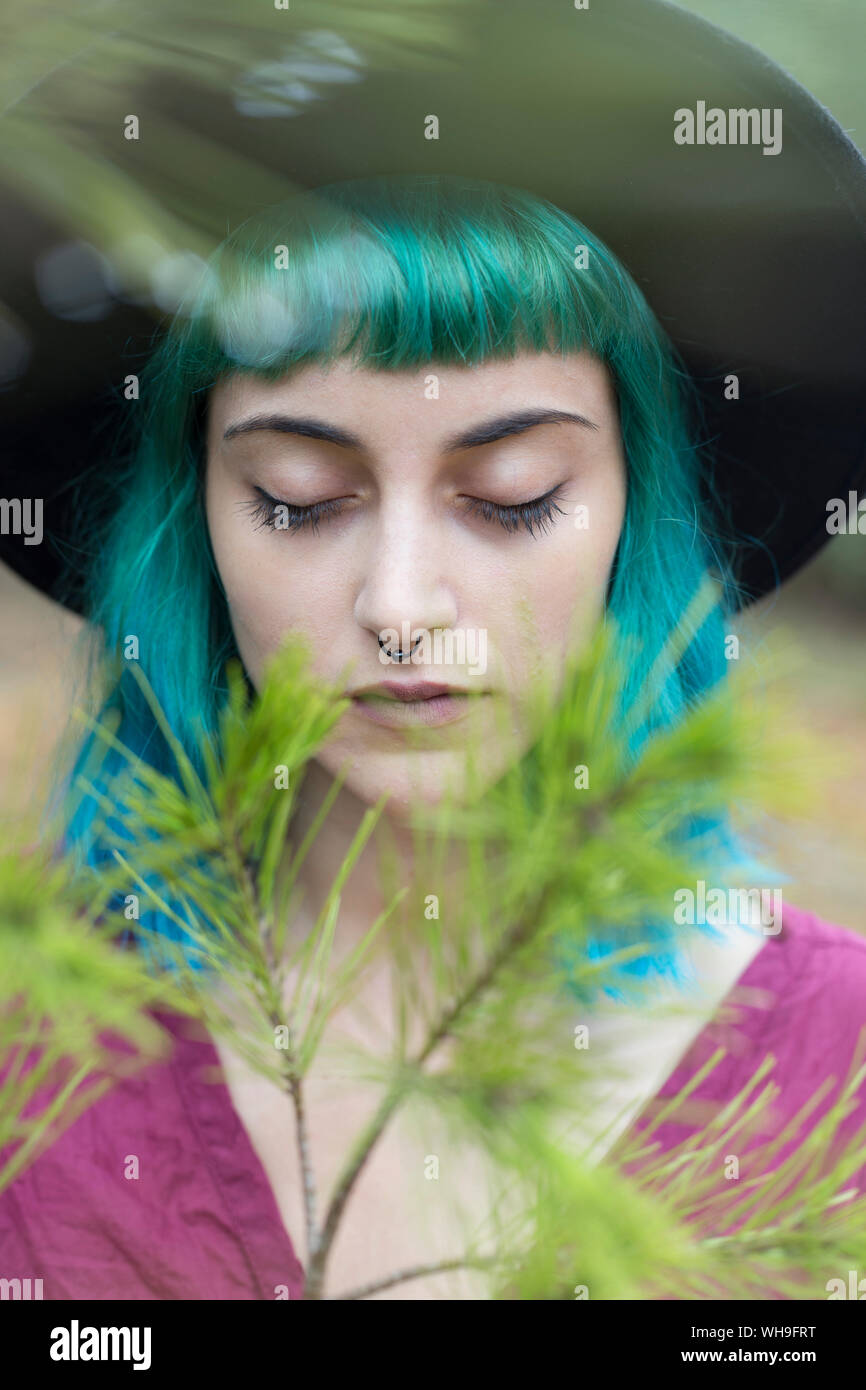 Ritratto di giovane donna con tinti di blu e verde per i capelli e piercing per il naso in natura Foto Stock