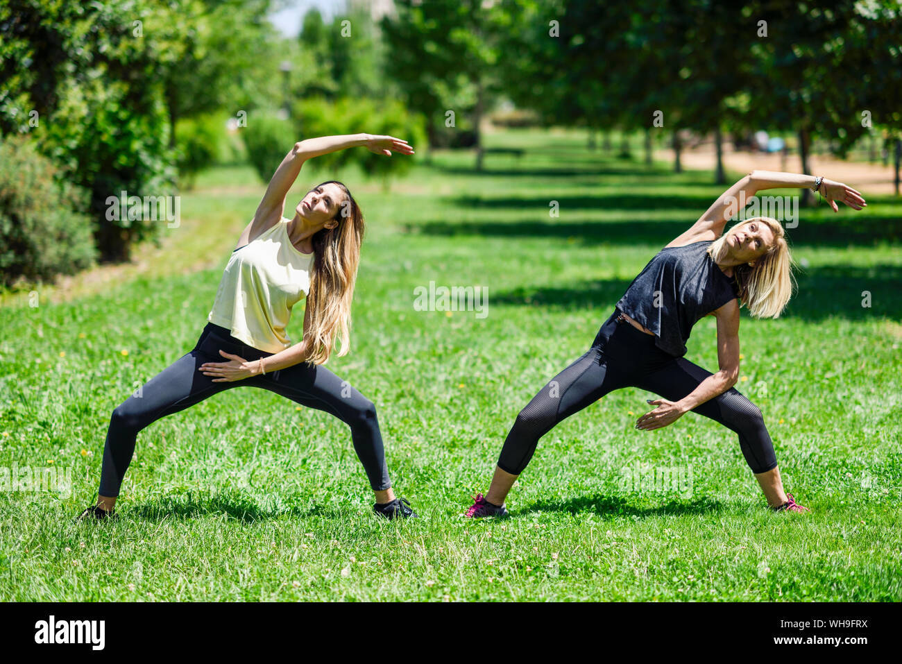 Donna matura a praticare lo yoga con sua figlia in un parco Foto Stock
