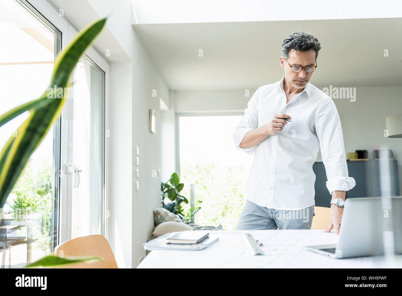 Architetto lavora sul progetto in un luminoso ufficio con computer portatile Foto Stock