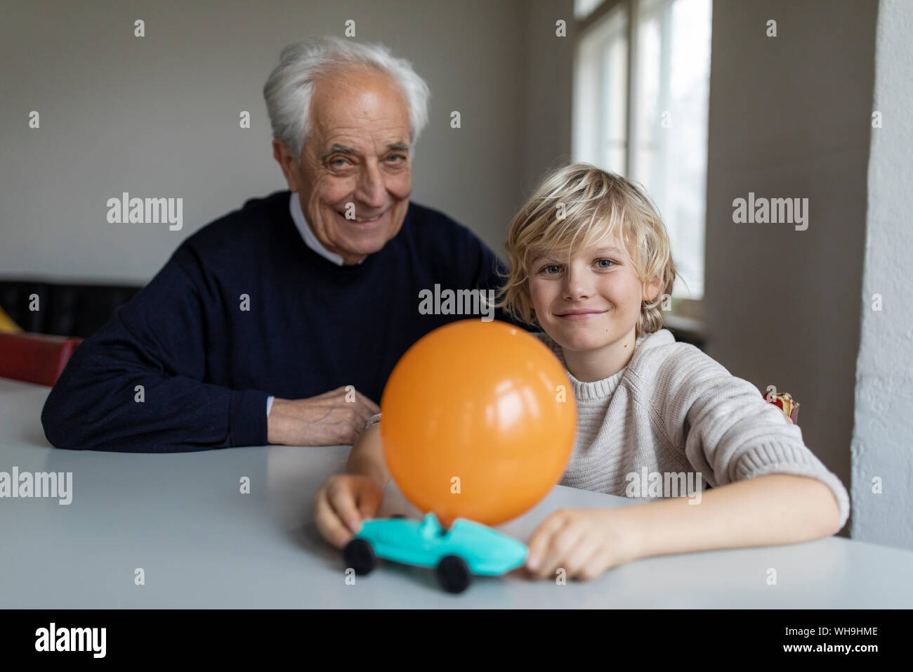 Felice nonno e nipote giocare con auto giocattolo e il palloncino a casa Foto Stock