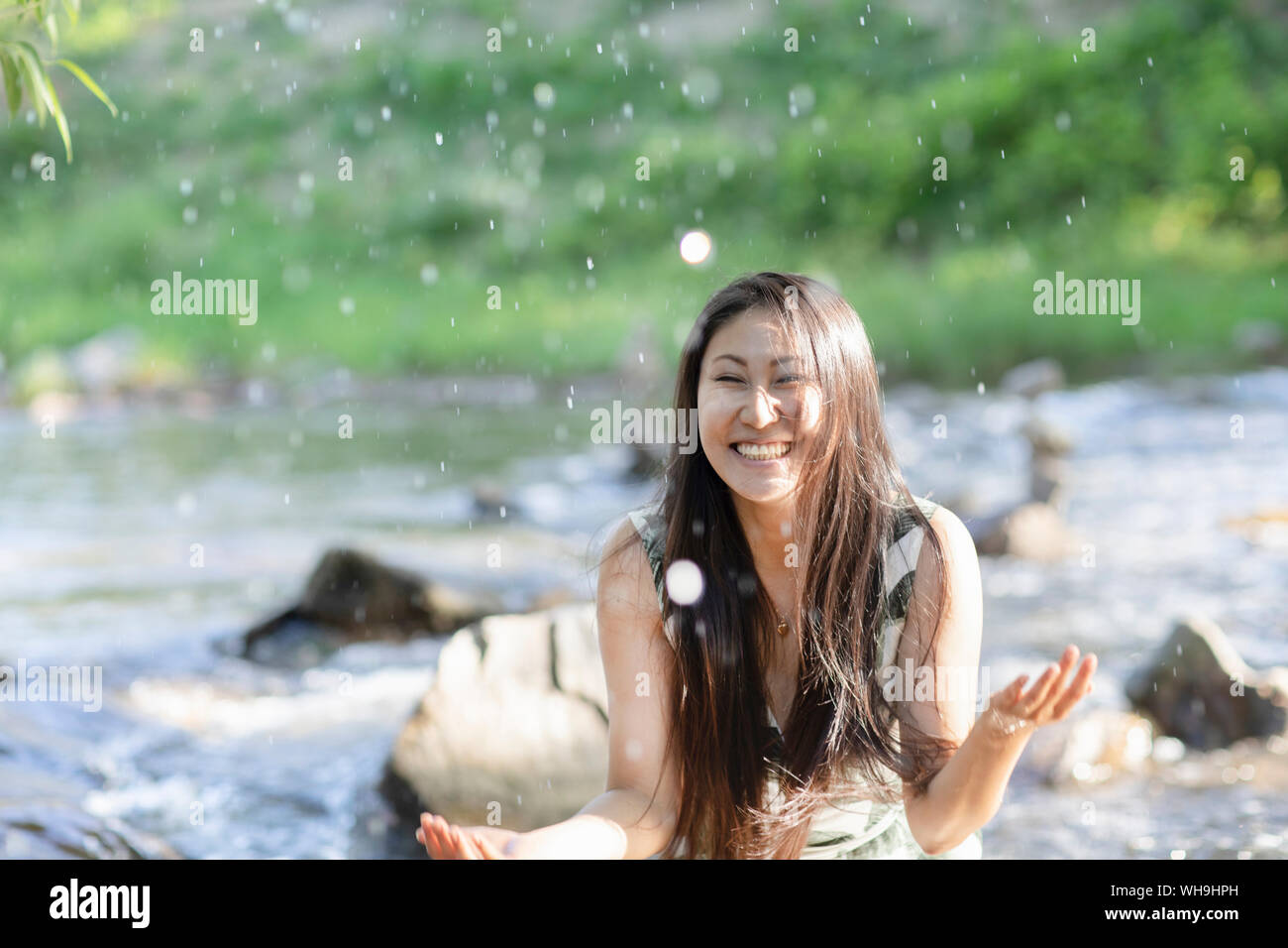 Giovane donna spruzzi in un fiume Foto Stock