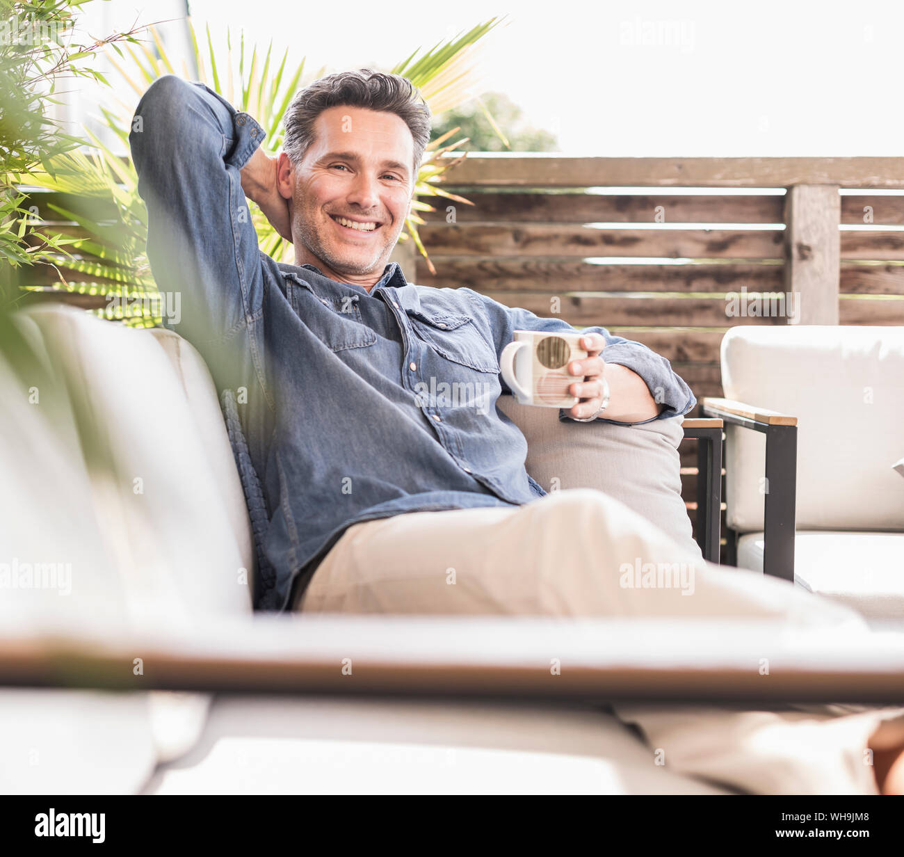Fiducioso uomo rilassarsi sulla terrazza, a bere caffè Foto Stock