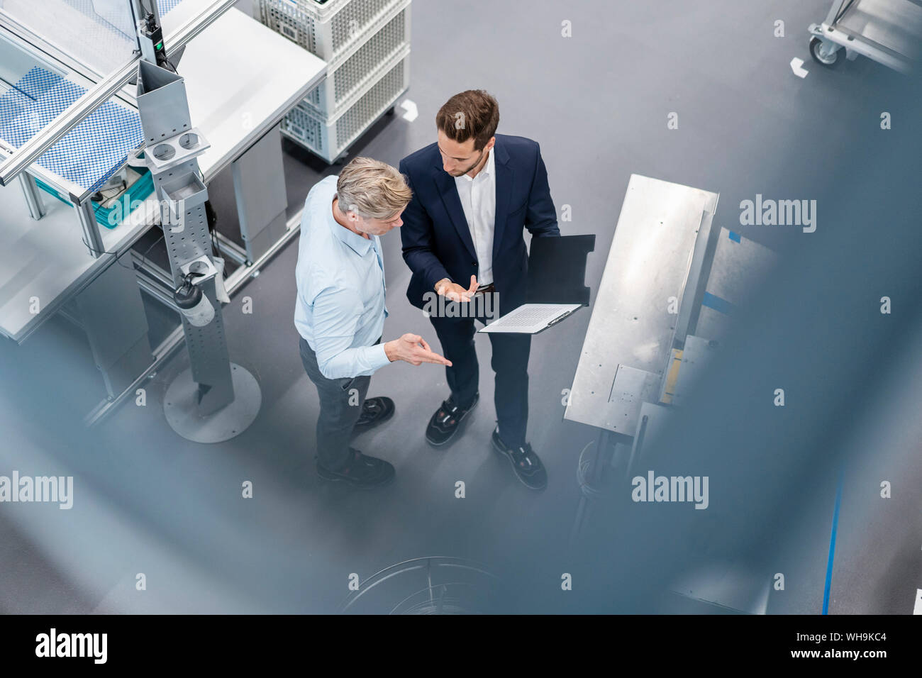 Due imprenditori con appunti parlando in una fabbrica Foto Stock