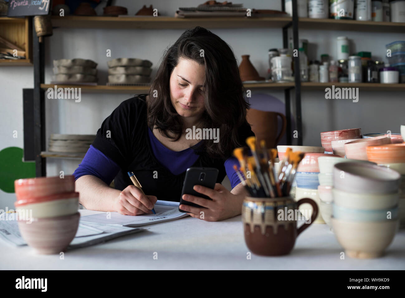 Potter facendo contabilità nella sua officina Foto Stock
