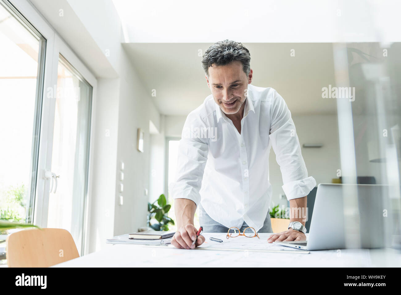 Architetto lavora sul progetto in un luminoso ufficio con computer portatile Foto Stock