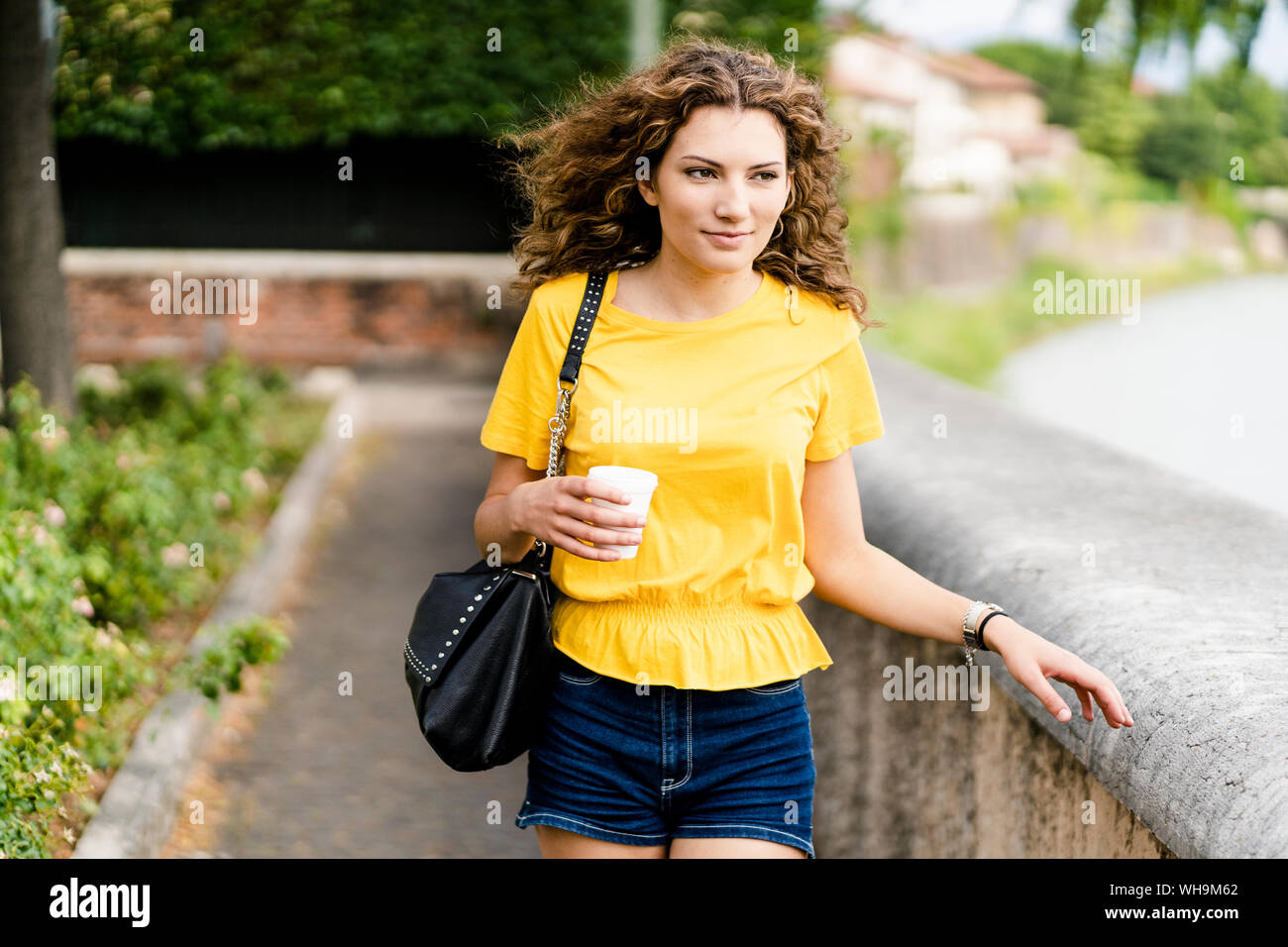 Giovane donna a camminare in città con tazza monouso Foto Stock