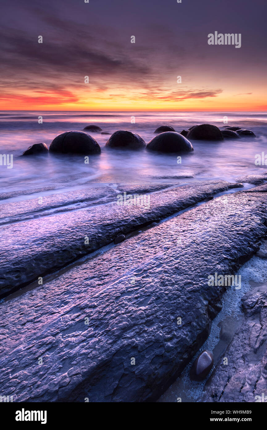 I massi Moeraki con drammatica alba alla spiaggia Moeraki, Otago, South Island, in Nuova Zelanda, Pacific Foto Stock