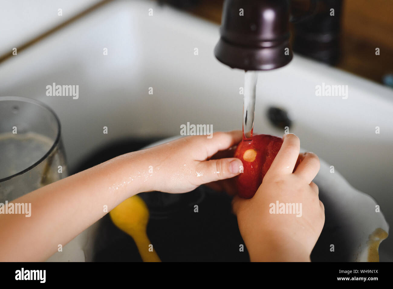 Little Boy lavaggio mani di pesche in cucina, close-up Foto Stock