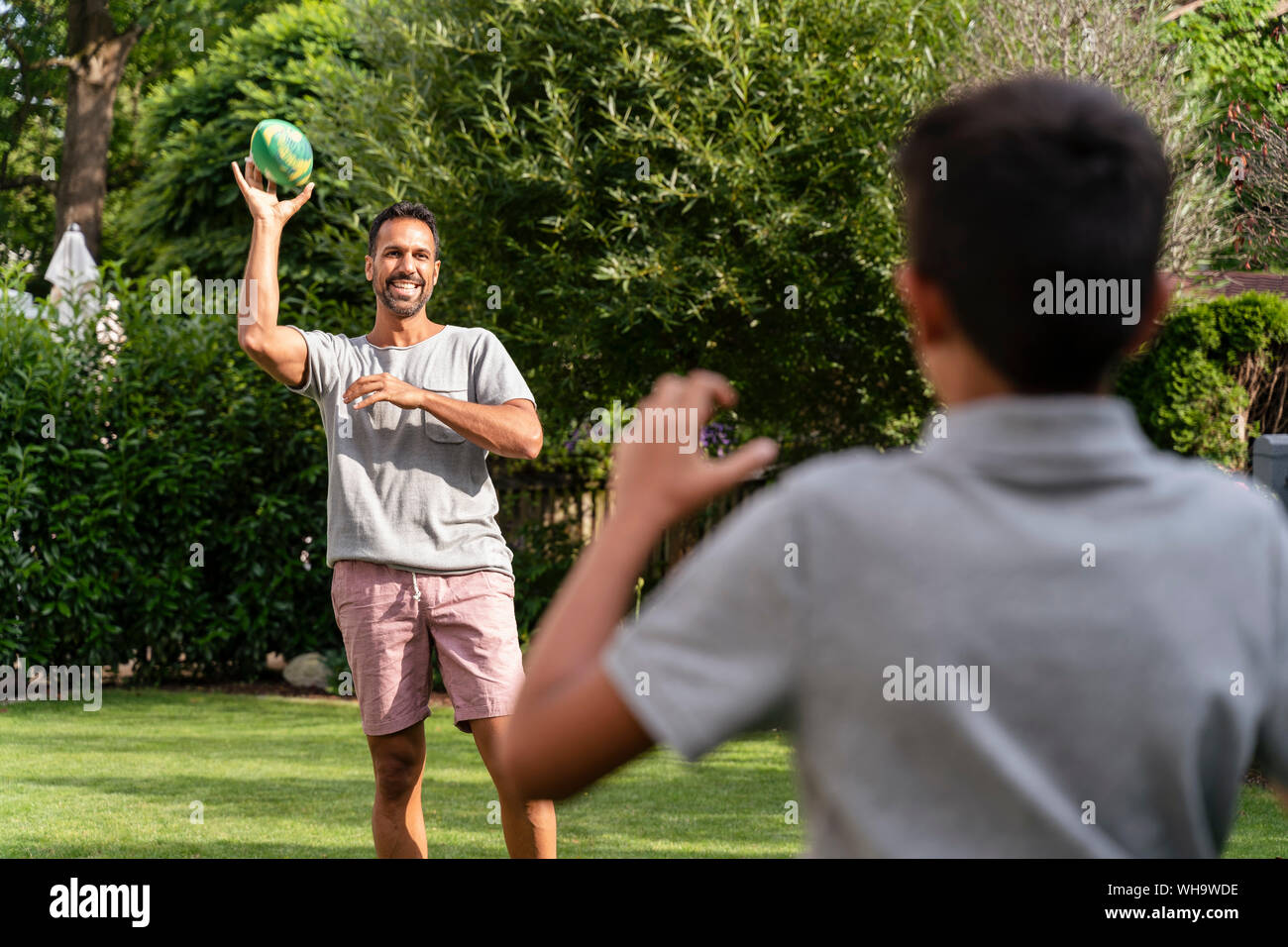 Padre e figlio giocando con il football americano in giardino Foto Stock