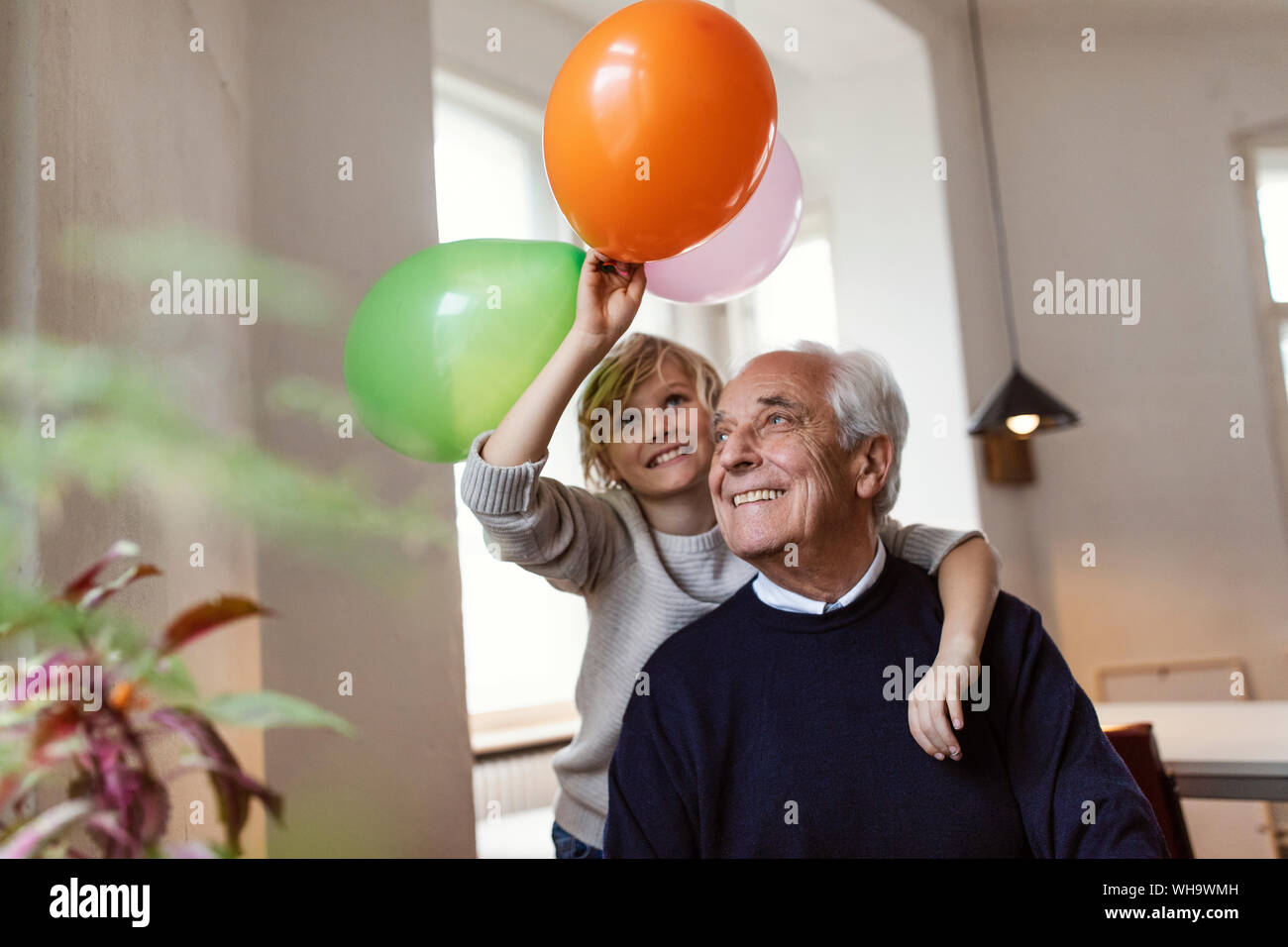 Felice nonno e nipote giocando con palloncini a casa Foto Stock