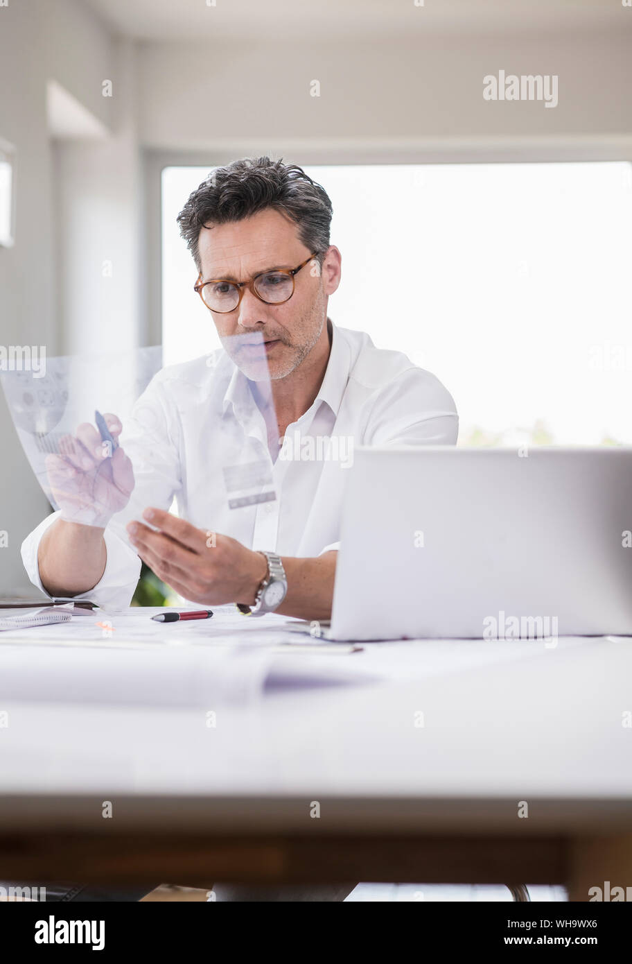 Arcitect preparare la presentazione, seduta in ufficio guardando il foglio piano Foto Stock