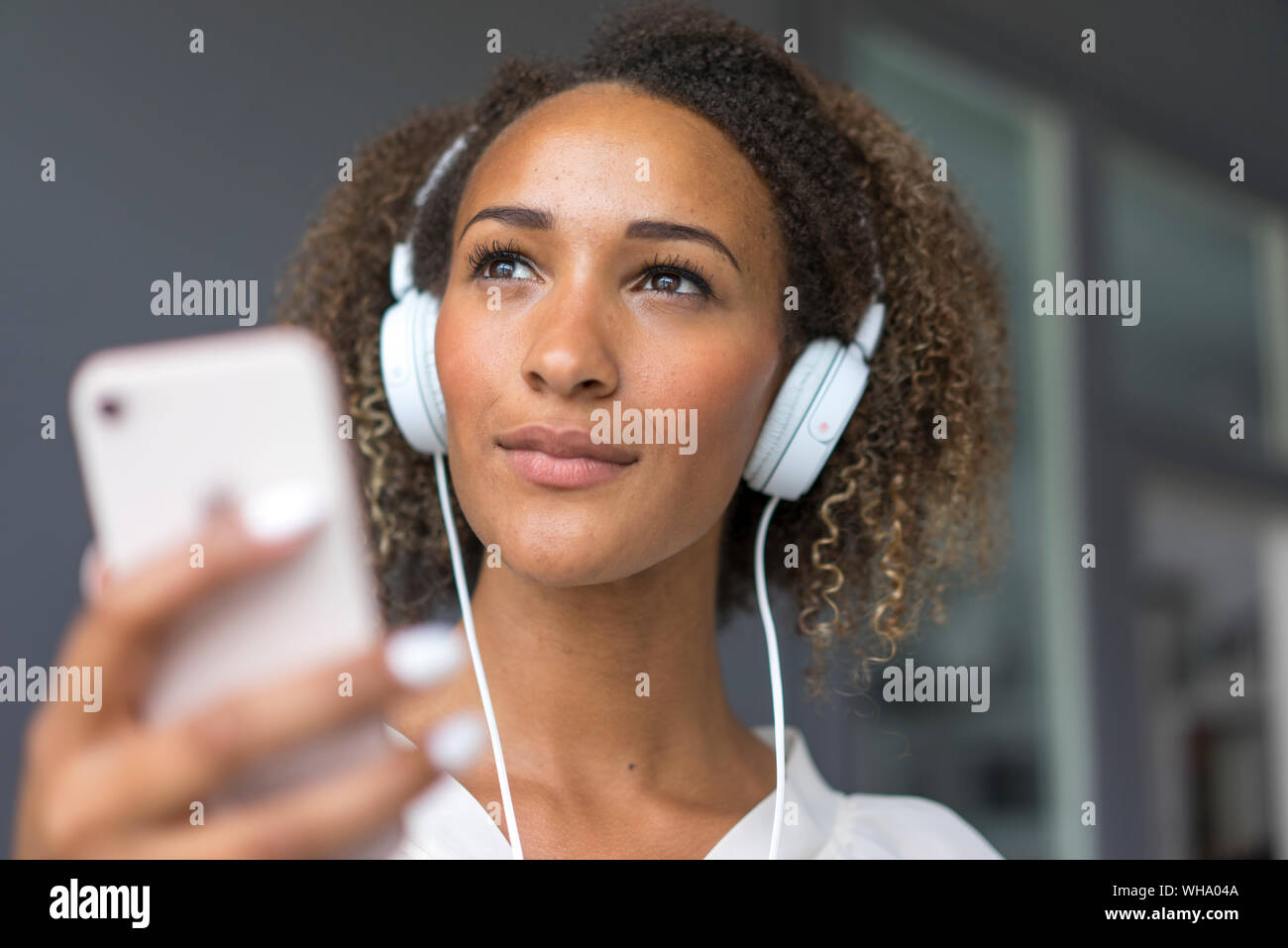 Ritratto di giovane donna con lo smartphone e cuffie bianche Foto Stock