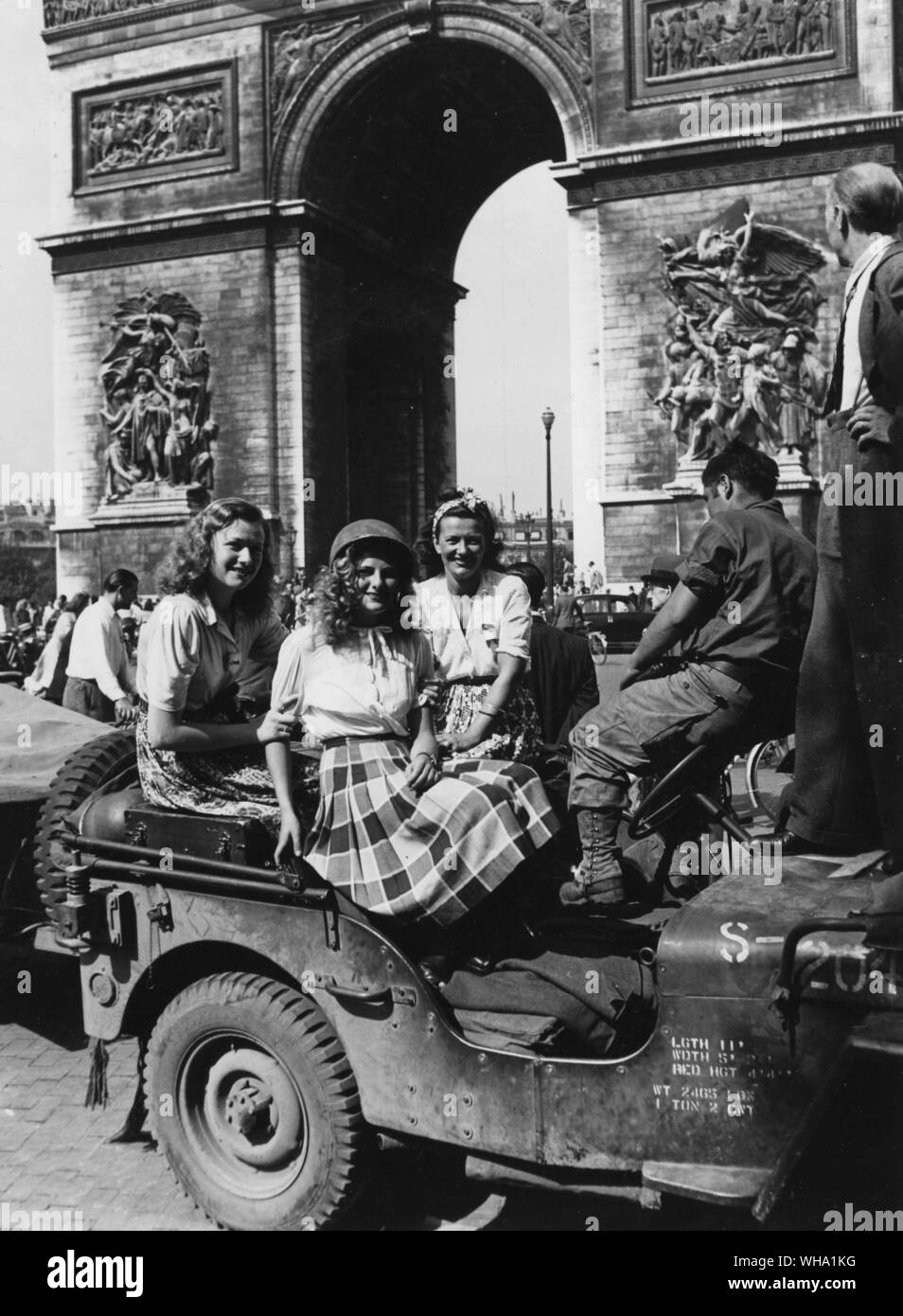 WW2: la liberazione di Parigi, Agosto 1944. Civile delle donne che indossano caschi militari con l'Arc de Triomphe in background. Place de L'Etoile. Foto Stock