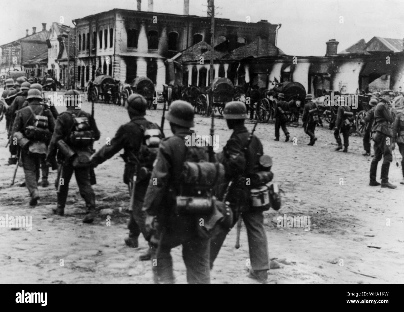 WW2: la Russia. Gli edifici sulla destra, non distrutto da gusci sono tuttavia bruciata, eventualmente da russi lasciare la città mentre effettuate la terra bruciata editto di Stalin. Le truppe tedesche si muovano per catturare il nuovo territorio. I carri di alimentazione a destra. Foto Stock