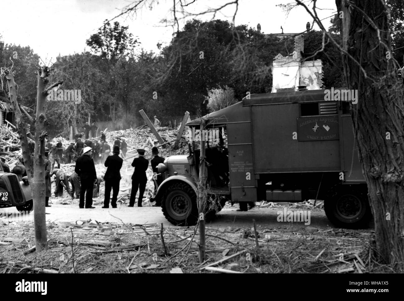 WW2: Sito di un incidente. Difesa civile soccorritori ascoltare e scavare per vittime intrappolata sotto cumuli di macerie. In primo piano è una delle ambulanze donati alla Gran Bretagna dagli USA. Questi sono gestiti da American ambulanza, Gran Bretagna, che è stato sostenuto da guerra britannica della società. Foto Stock