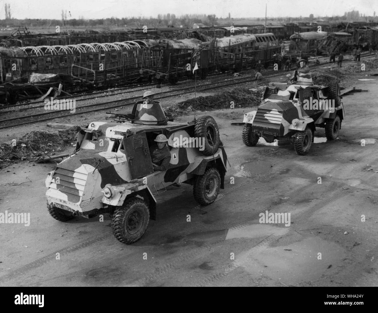 WW2: RAF auto blindate di pattuglia al di fuori di Salonicco, con uno sfondo del relitto di una materiale rotabile distrutto dagli attacchi di RAF. Foto Stock