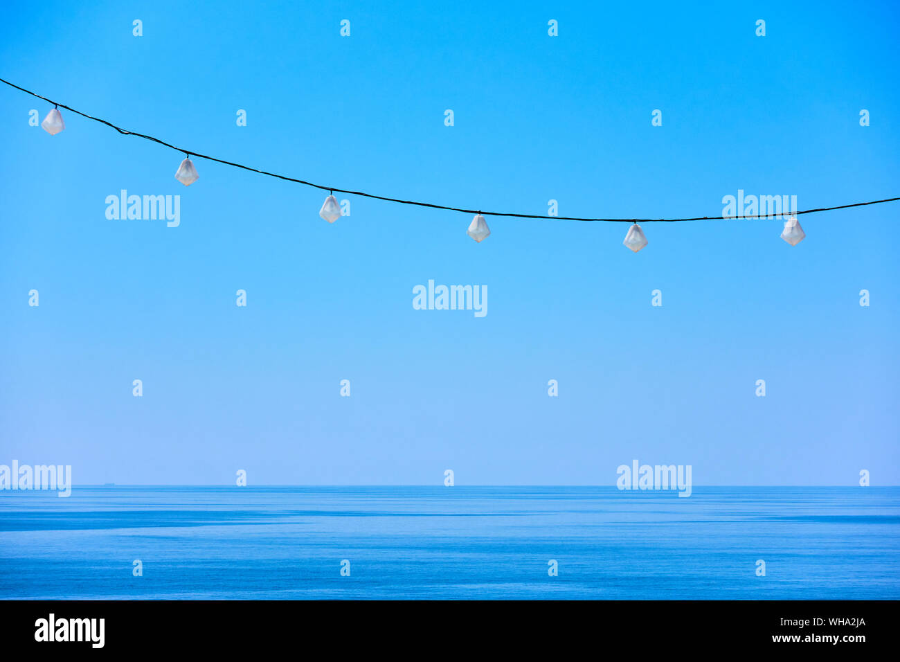 Mare orizzonte, cielo blu chiaro e stringa decorativo delle luci delle vacanze - sfondo con spazio per il testo Foto Stock