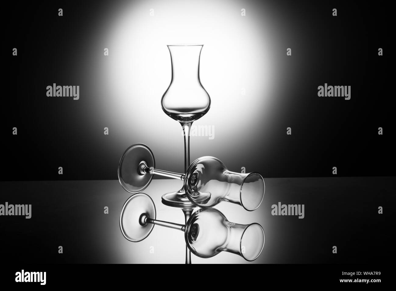 Due classici ed eleganti bicchieri per grappa italiana di retroilluminazione, con riflessione Foto Stock