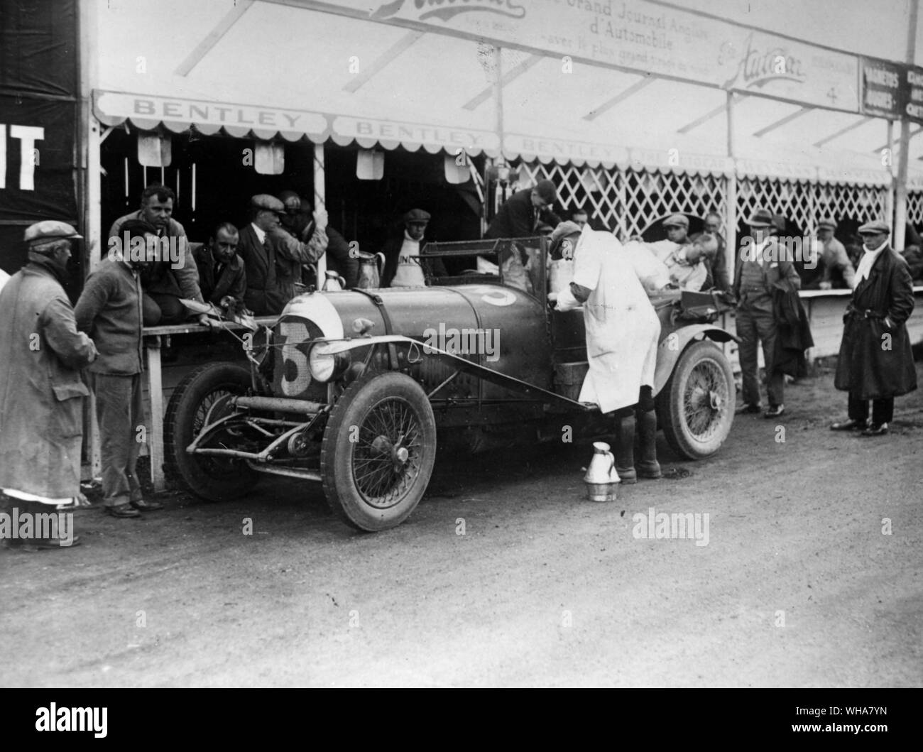 Le Mans 1927 Vecchio Numero 7 3 litro Bentley al box di essere nuovamente riempito dal dr. J D Benjafield mentre R A Clarke inginocchiarsi e W O Bentley accanto a lui e Sammy Davis nel casco in piedi Foto Stock