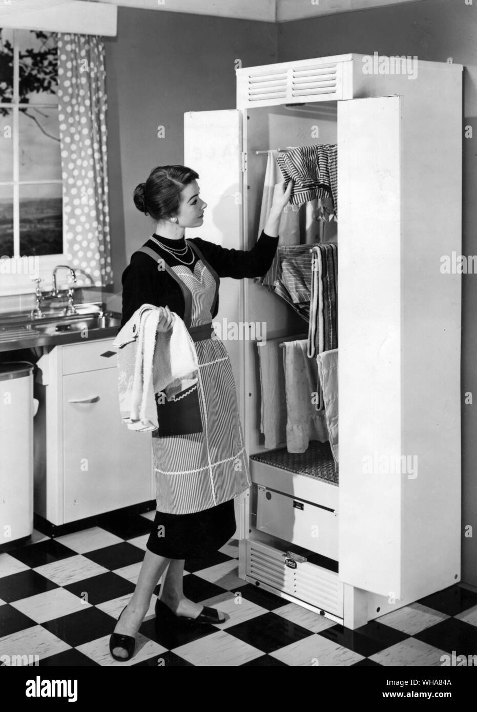 Donna di riagganciare il lavaggio in un gas riscaldato cabinet Foto Stock