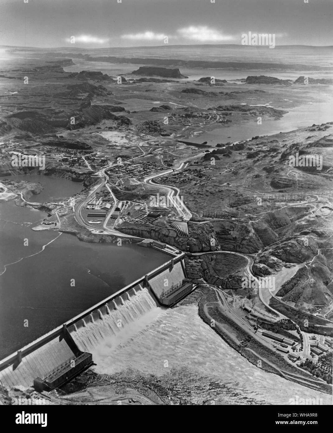 Grand Coulee Dam nello Stato di Washington, lungo una delle nazioni top attrazioni turistiche, è la più grande struttura di cemento mai costruito dall'uomo. Lo spruzzo di dodici tubi al centro dell'immagine sono le uscite per l'acqua pompata dalla piscina dietro la diga nel Grand Coulee sopra. Qui l'acqua viene memorizzato per il rilascio a irrigare i milioni di acri di Columbia Basin progetto di irrigazione a sud. La diga è di 46 storie alta, superiore al Monumento di Washington. Si tratta di 12 isolati della città lungo, 500 metri di spessore in corrispondenza della sua base. Colore ora illuminata anche di notte, i visitatori sono trasfissate come 120 diversi Foto Stock