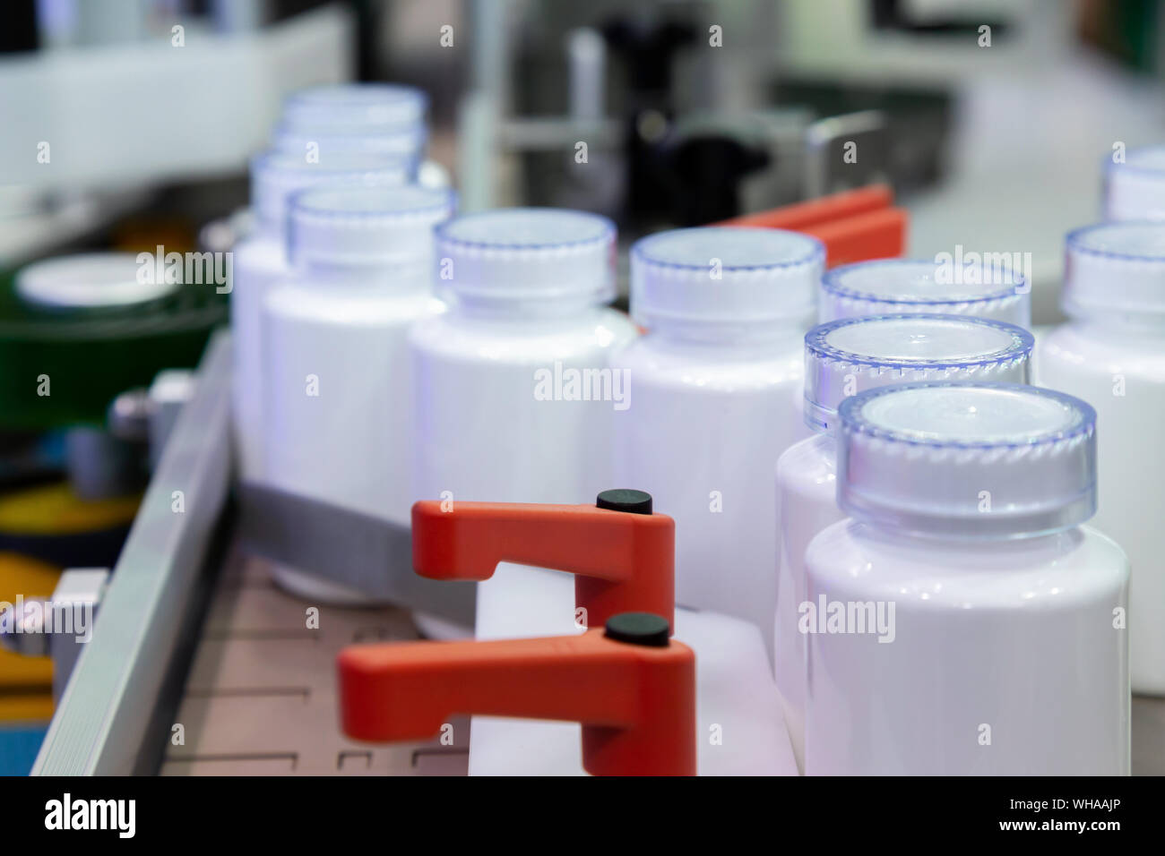 Bottiglia di plastica bianca sulla linea di produzione del nastro alla macchina di riempimento in fabbrica. Il fuoco selettivo. Foto Stock