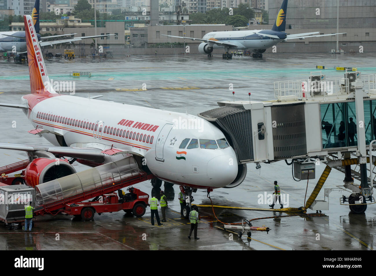 INDIA, Mumbai , Aeroporto Internazionale di Chatrapati Shivaji, Airbus di Air India, il personale di terra del team di servizio e di imbarco passeggero sul ponte di imbarco, dietro lo skyline di Mumbai e aerei di compagnie aeree private Jet Airways che sono andati in fallimento nel 2019 Foto Stock