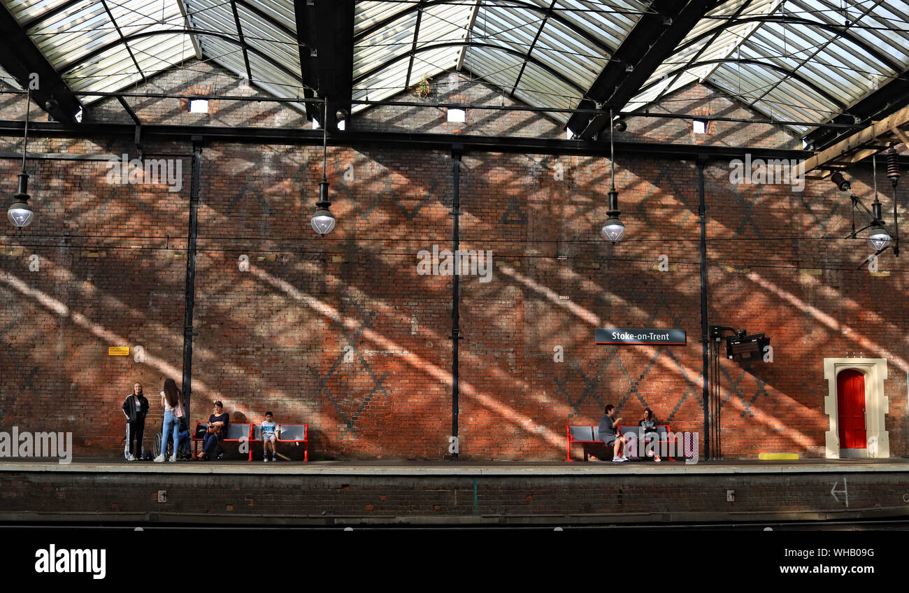 Forte sole estivo crea ombre come passeggeri attendere un treno in direzione nord a Stoke on Trent ferrovia 23.8.19. Foto Stock