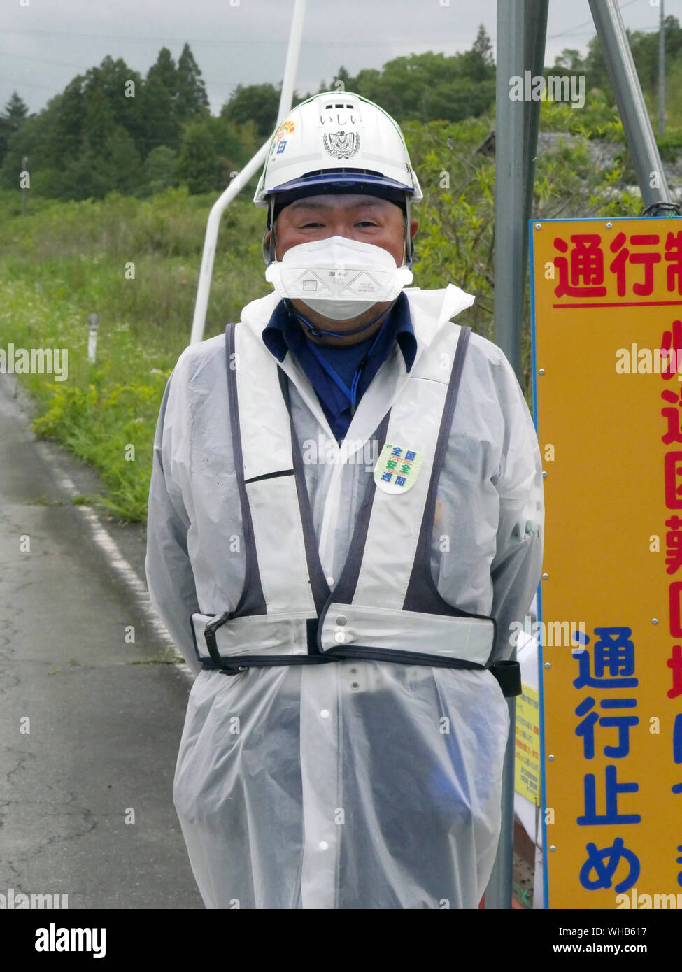 Visita Minamisoma, nel quartiere Haramachiku, una città duramente colpita dalla radiazione perdita dalla Fukushima Daiichi e daini centrali nucleari dopo il terremoto e lo tsunami. Guardia di sicurezza evitando il traffico proveniente da entrare insicure zone radioattive. Foto Stock