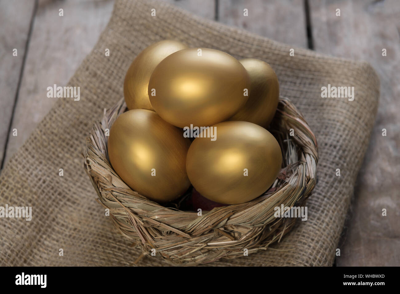 Piccolo gruppo di golden uova di pasqua nel nido di uccelli oltre rustico sfondo legno close-up, orientamento orizzontale Foto Stock