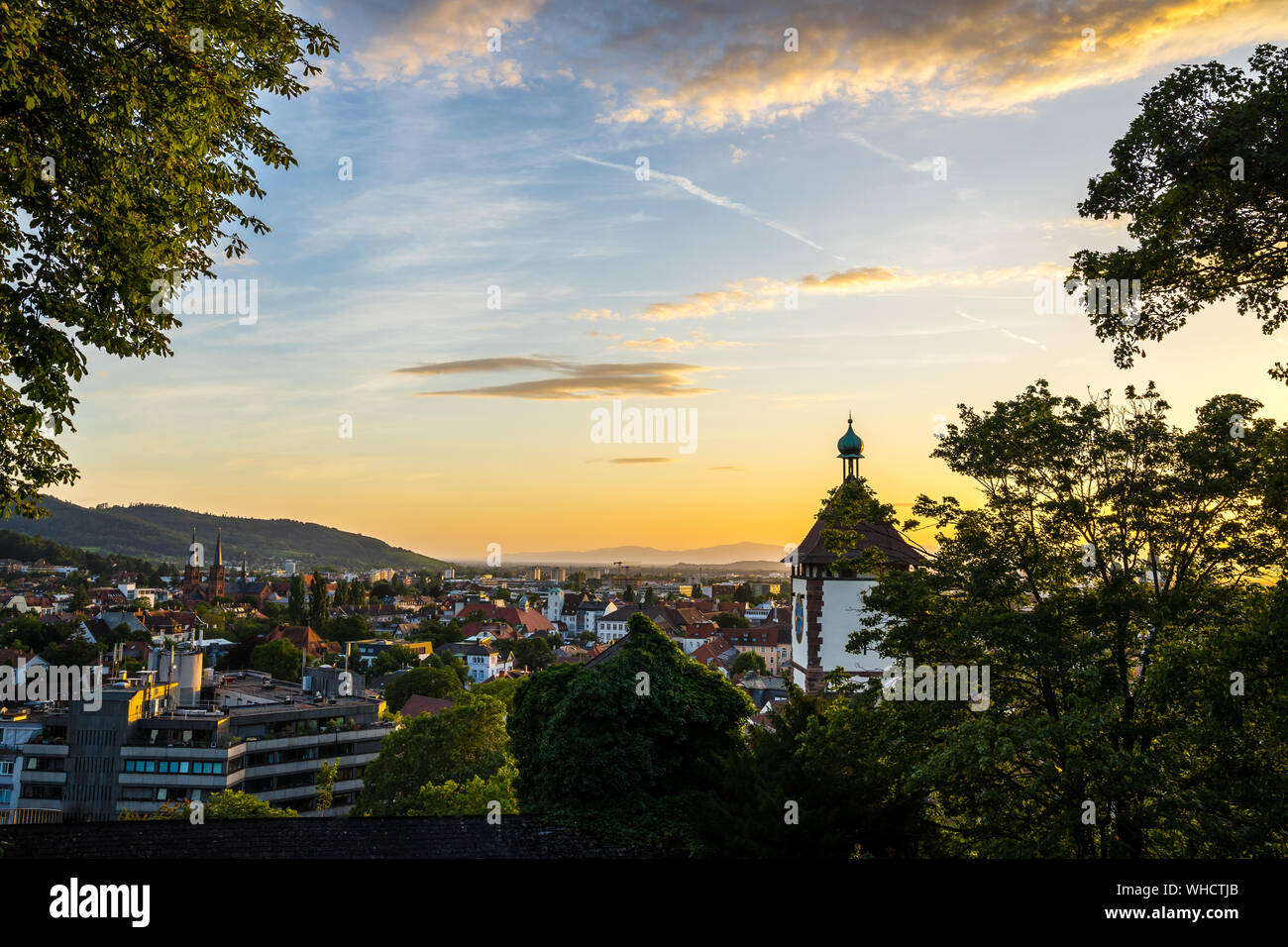Germania, bella calda luce del tramonto che brilla sulla famosa città vecchia schwabentor gate in Freiburg im Breisgau, visto da sopra lo skyline della città in summe Foto Stock