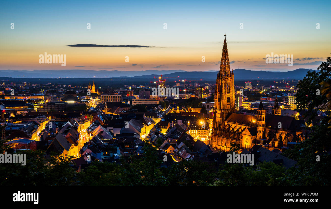 Germania, Freiburg im Breisgau cityscape e minster o muenster cattedrale nella magica atmosfera dopo il tramonto in estate dalla famosa piazza sopra il ci Foto Stock