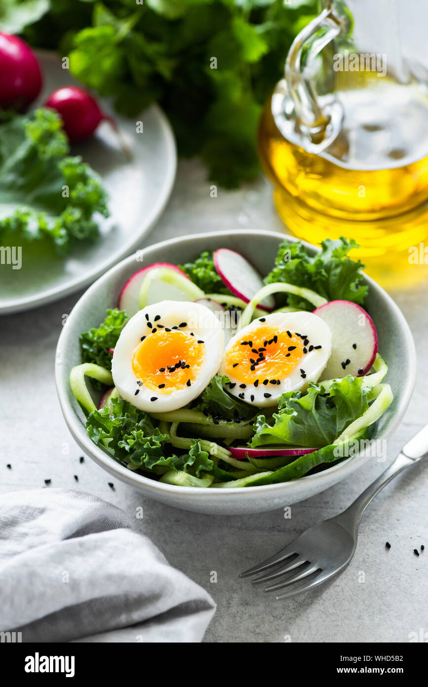 Una sana insalata verde con kale, cetriolo, uova e ravanelli nel recipiente. Insalata primaverile Foto Stock