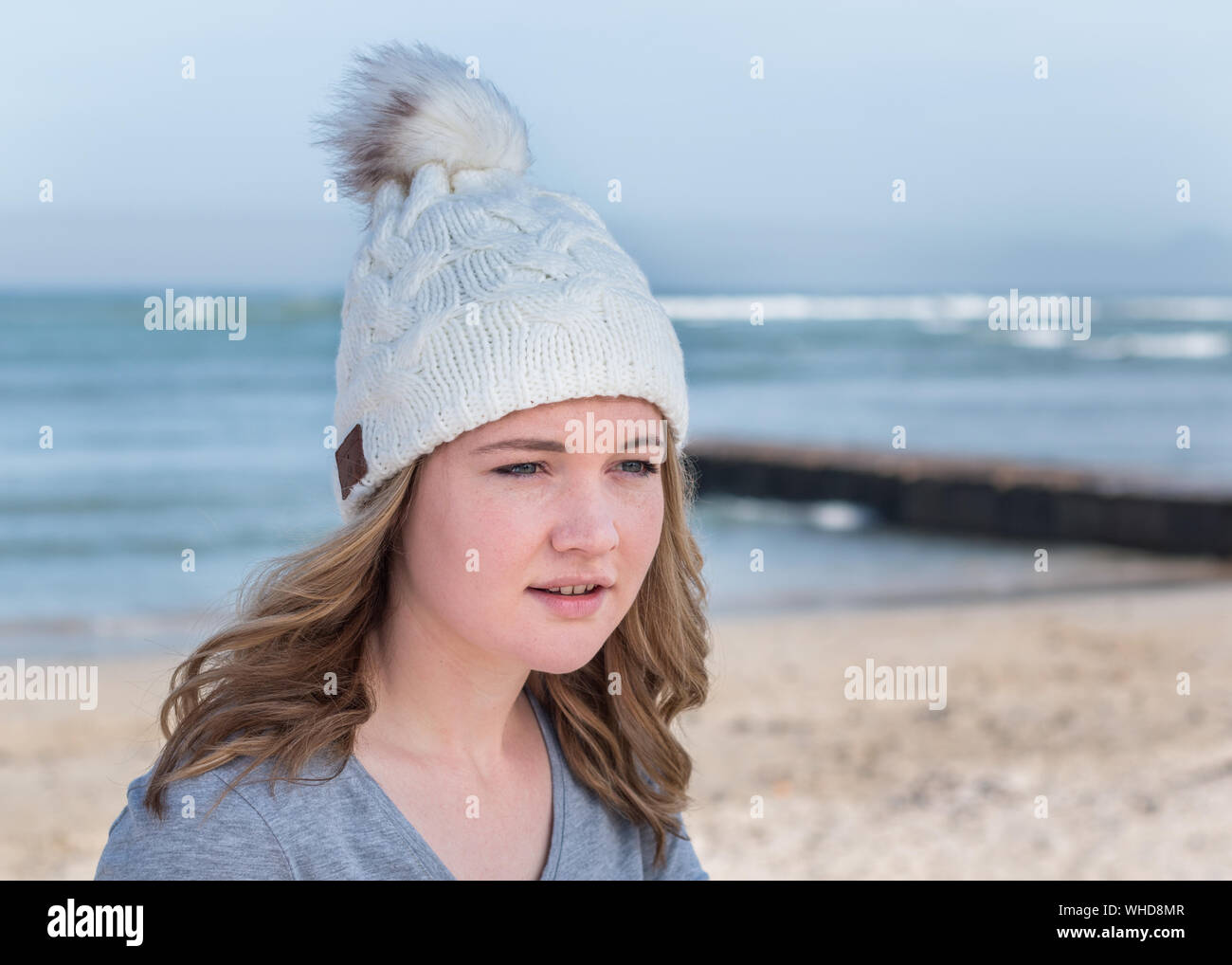 Modello femminile che indossa bianco maglia beanie con altoparlanti Bluetooth Foto Stock