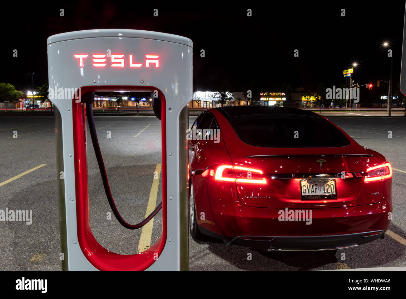 Tesla Model S collegata alla stazione Supercharger Tesla di notte. Foto Stock