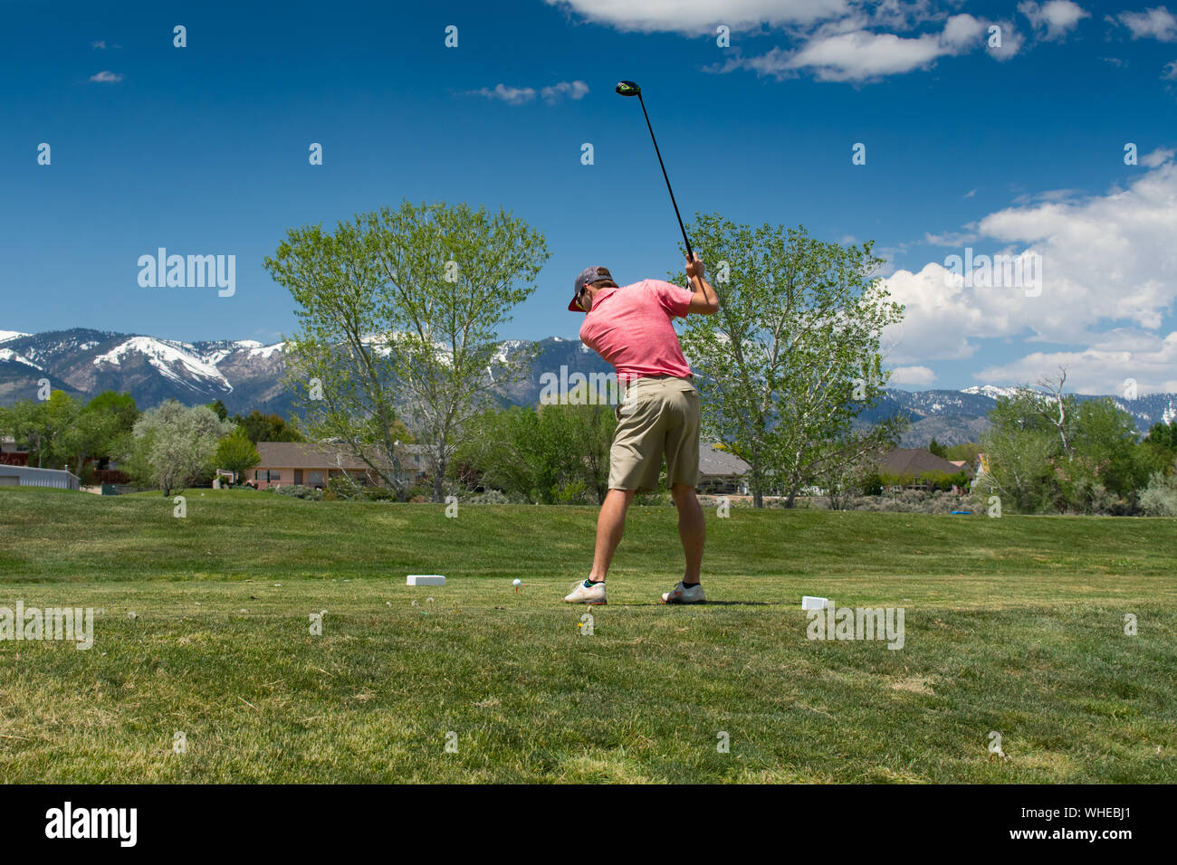 Giocatore di golf maschile nelle montagne di colpire tee-shot con conducente Foto Stock