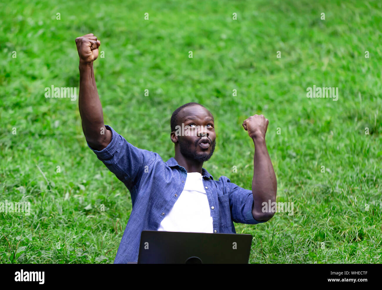 Espressivo giovane africano-studente americano celebra il suo successo accademico all'aperto Foto Stock