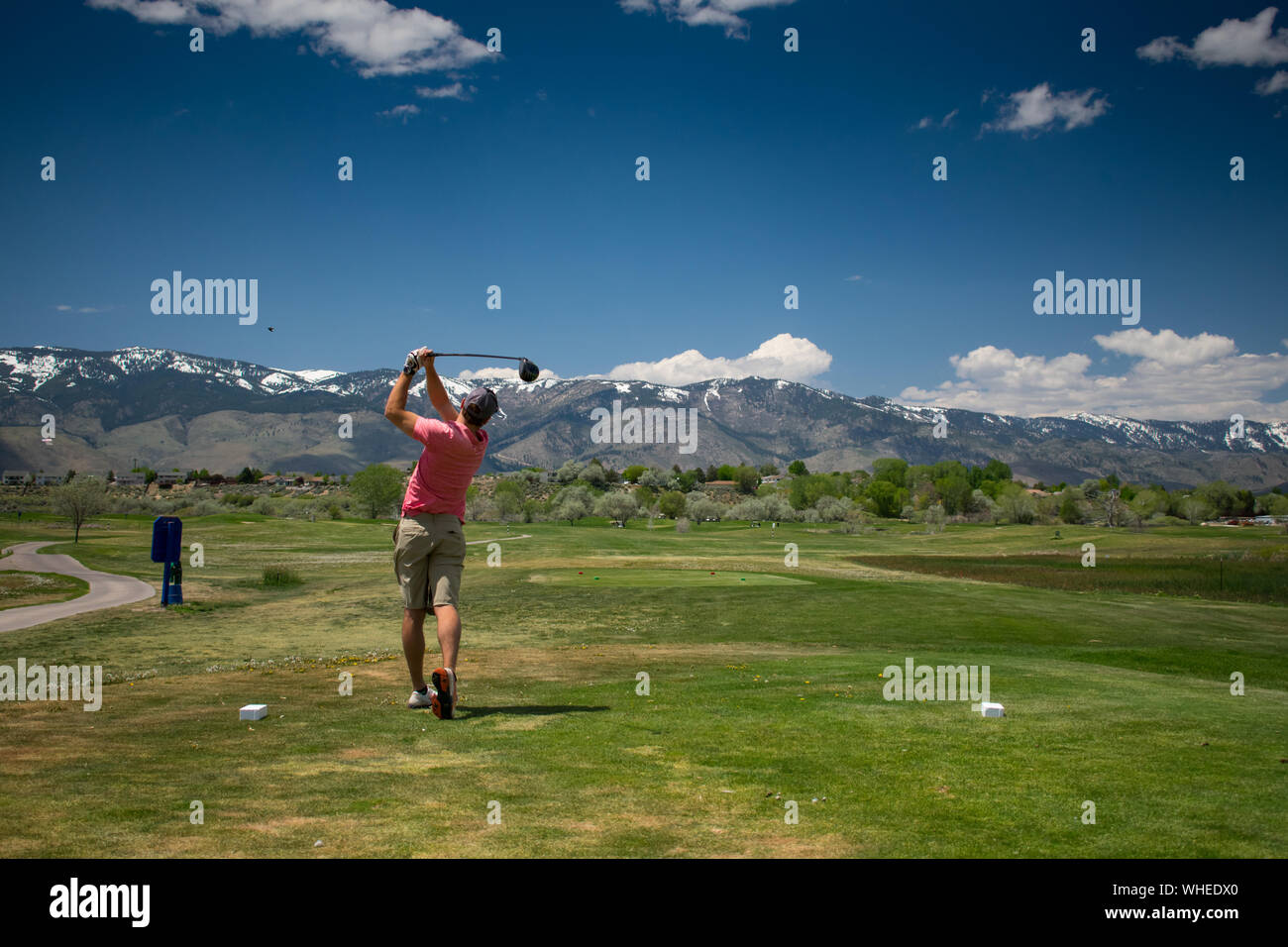 Giocatore di golf maschile nelle montagne di colpire tee-shot con conducente Foto Stock